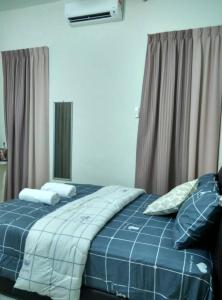 uma cama com lençóis e almofadas azuis num quarto em Homestay Mama D'Chandan em Kuala Kangsar