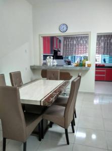 uma sala de jantar com mesa e cadeiras e um relógio em Homestay Mama D'Chandan em Kuala Kangsar