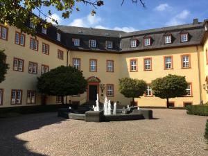 a large building with a fountain in the courtyard at Ferienwohnung am Wald in Hachenburg