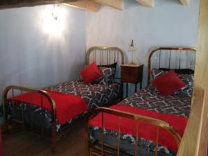 La Belle Maison في Piégut-Pluviers: سريرين في غرفة مع وسائد حمراء