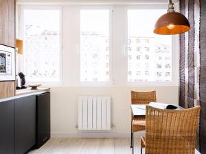 a kitchen with a table and chairs and windows at HABITAKA, Hogares de paso in Vitoria-Gasteiz