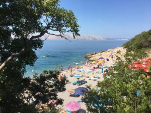 a group of people on a beach with umbrellas at Apartman Mimoz in Senj
