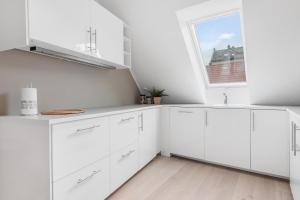 cocina blanca con armarios blancos y ventana en Fosswinckel Apartments, en Bergen