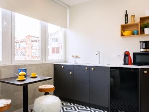 a kitchen with black cabinets and a stool and a table at HABITAKA, Hogares de paso in Vitoria-Gasteiz +8 photos