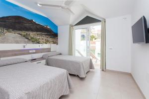 a hotel room with two beds and a tv at TAO Caleta Playa in Corralejo