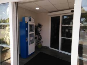 Un distributeur automatique bleu et blanc est installé à côté d'une porte. dans l'établissement ibis budget Aix en Provence, à Aix-en-Provence