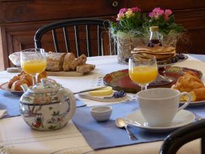 - une table avec un petit-déjeuner composé de jus d'orange et de viennoiseries dans l'établissement La Mirandole, à Foix
