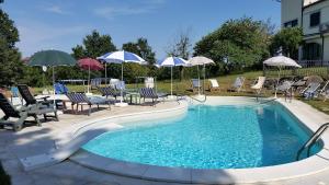 una gran piscina con sillas y sombrillas en Cascina Rosa Camilla, en Carpeneto