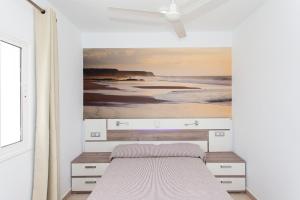 a bedroom with a bed with a painting on the wall at TAO Caleta Playa in Corralejo