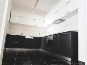 a kitchen with white cabinets and black tile floors at Apartments Villa White House in Pančevo