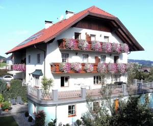 ein weißes Gebäude mit Blumen auf den Balkonen in der Unterkunft Pension Waldhof in Koppl