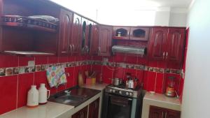 a red kitchen with a sink and a stove at Hostel Puno Backpackers in Puno