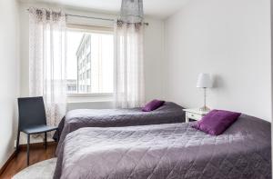 two beds in a bedroom with purple pillows and a window at Apartment Pohjantähti in Oulu