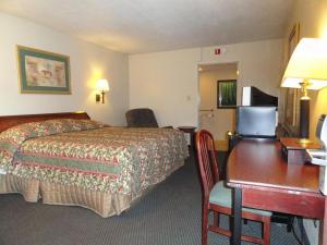 a hotel room with a bed and a desk at Red Carpet Inn (formerly Royal Inn) in Terre Haute