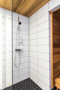 a bathroom with a shower with white tiled walls at Apartment Pohjanpoika in Oulu