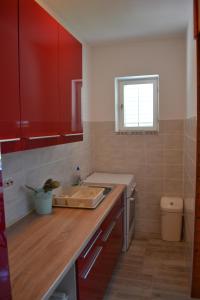 a kitchen with red cabinets and a sink at Danijela in Mali Lošinj