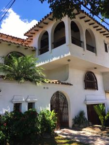 a white house with arched windows and a gate at Oasis en el corazón de Medellin, Laureles in Medellín