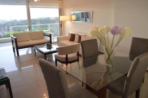 a living room with a glass table with a vase of flowers at Balena Bianca I Deck in Punta del Este