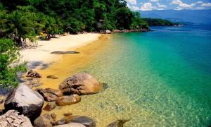 a beach with rocks and the water and trees at Recanto Mirim in Paraty