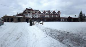 a large house with a snow covered driveway at Pensiunea la Nise in Sîmbăta de Sus