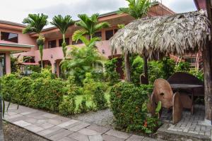 a garden in front of a pink building at Hotel La Choza Inn in Fortuna