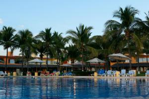 een resort met palmbomen en stoelen en een zwembad bij Villas Playa Blanca in Zihuatanejo
