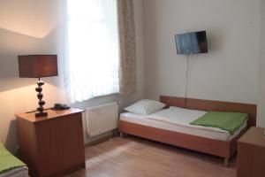 グダニスクにあるDom Sonataのベッド2台、壁掛けテレビが備わる小さな客室です。