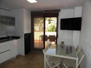 une cuisine avec une table blanche et une télévision dans l'établissement Apartamento Terrazas de Monachil, à Monachil