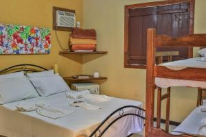ein Schlafzimmer mit einem Bett und einem Etagenbett in der Unterkunft Pousada Das Araras in Itaúnas