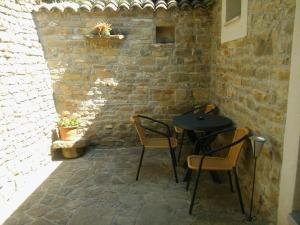 a patio with a table and chairs in a brick wall at Apartment Staleta Tartuf in Livade