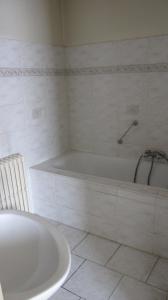 a white bathroom with a tub and a white tile floor at Hotel Manhattan in Brussels