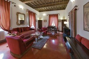 ein Wohnzimmer mit roten Sofas und einem Tisch in der Unterkunft Residenze d'Epoca Palazzo Coli Bizzarrini in Siena