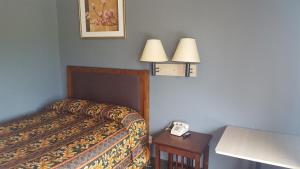 a room with a bed and a table with a phone at Travel Inn in Sharonville
