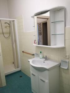 Un baño con lavabo y ducha con espejo. en Appartamento l'Approdo, en Castiglione della Pescaia