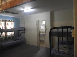 a room with three bunk beds and a bathroom at Kalbarri Backpackers YHA in Kalbarri