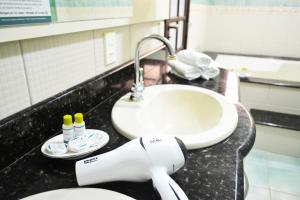 a bathroom counter with a white sink and a toilet at Pousada Canasvieiras in Florianópolis