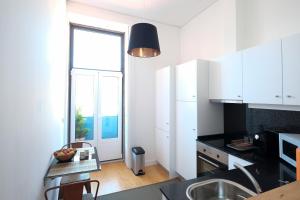 uma cozinha com armários brancos e uma grande janela em Porto Duke's House no Porto