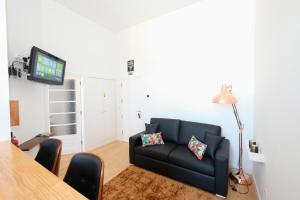 a living room with a black couch and a tv at Porto Duke's House in Porto