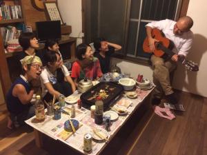 a group of people sitting around a table with a guitar at Fujiya in Matsuyama