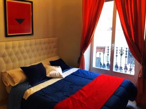 łóżko w sypialni z oknem z czerwonymi zasłonami w obiekcie BOOKINGHAM ★Apartaments & Suites w Madrycie