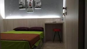 a bedroom with a bed and a table with a stool at SleepRest - Plamo Garden in Batam Center