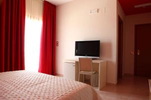 um quarto com uma cama e uma secretária com uma televisão em Casale degli Ulivi Resort em Pellare