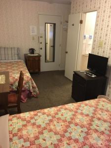 a hotel room with two beds and a television on a table at The Courtland Hotel & Spa in Fort Scott