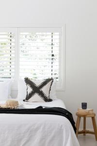 a bedroom with a white bed with a window at Satara Byron Bay - Adults Only in Byron Bay