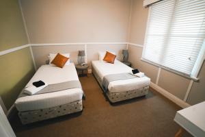 2 łóżka w małym pokoju z oknem w obiekcie The Greenroof w mieście Newcastle