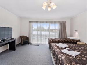 a hotel room with two beds and a flat screen tv at Cleveland Thermal Motel in Rotorua