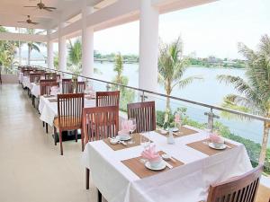 a restaurant with tables and chairs with a view of the water at Century Riverside Hue in Hue