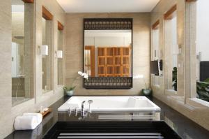 ein Badezimmer mit einer Badewanne und einem großen Spiegel in der Unterkunft The Samaya Seminyak Bali in Seminyak