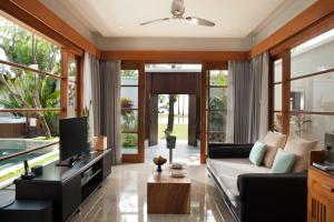 ein Wohnzimmer mit einem Sofa und einem TV in der Unterkunft The Samaya Seminyak Bali in Seminyak