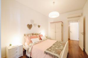 biała sypialnia z łóżkiem z różowymi poduszkami w obiekcie Casinha Azul w Lizbonie